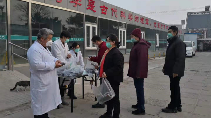 张海滨（左一）同医院医护人员为患者及附近居民免费赠送预防感冒中药_副本.jpg